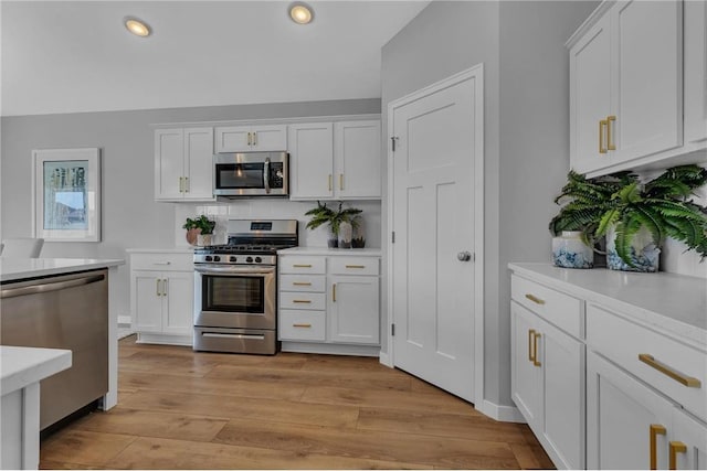 kitchen with white cabinets, tasteful backsplash, light hardwood / wood-style flooring, and stainless steel appliances