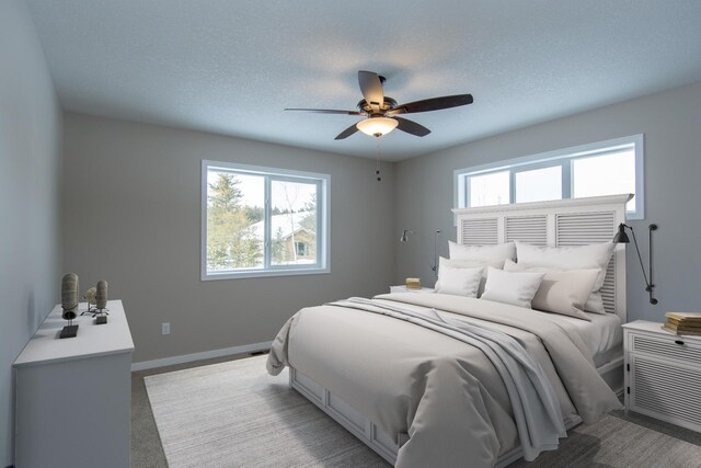 carpeted bedroom featuring ceiling fan, a textured ceiling, and multiple windows