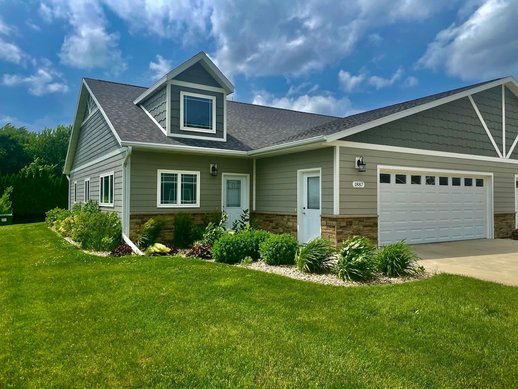 view of front facade featuring concrete driveway, stone siding, a front lawn, and an attached garage