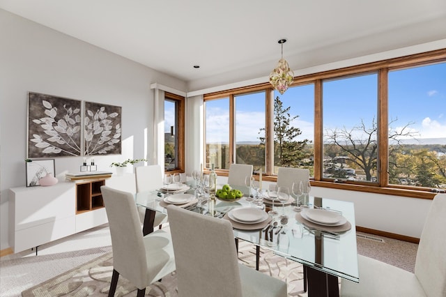 dining space featuring light carpet and an inviting chandelier