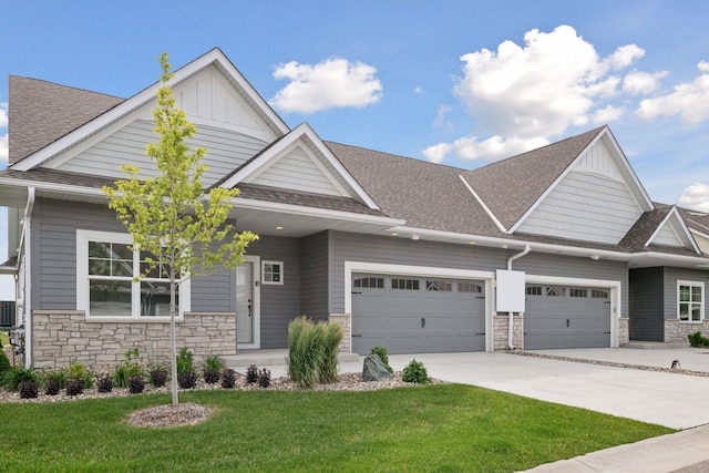 craftsman-style house featuring board and batten siding, a front yard, stone siding, and driveway