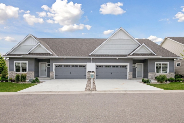 craftsman inspired home featuring driveway, stone siding, roof with shingles, an attached garage, and board and batten siding