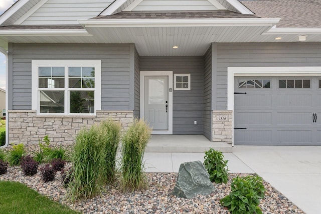 entrance to property with a garage, stone siding, and roof with shingles