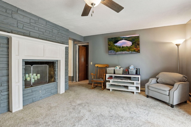 living area with a textured ceiling, a large fireplace, ceiling fan, and light colored carpet