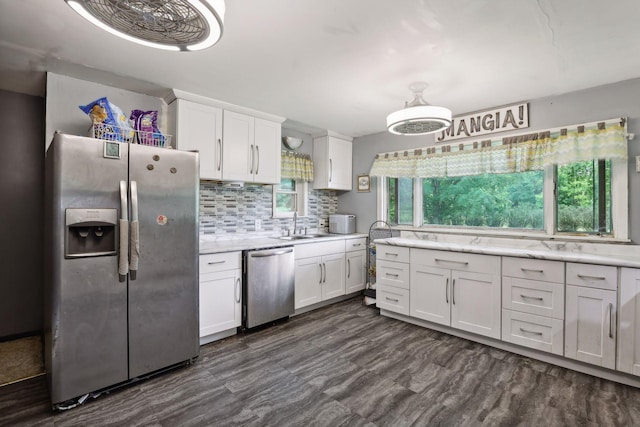 kitchen with appliances with stainless steel finishes, backsplash, dark wood-type flooring, and white cabinets