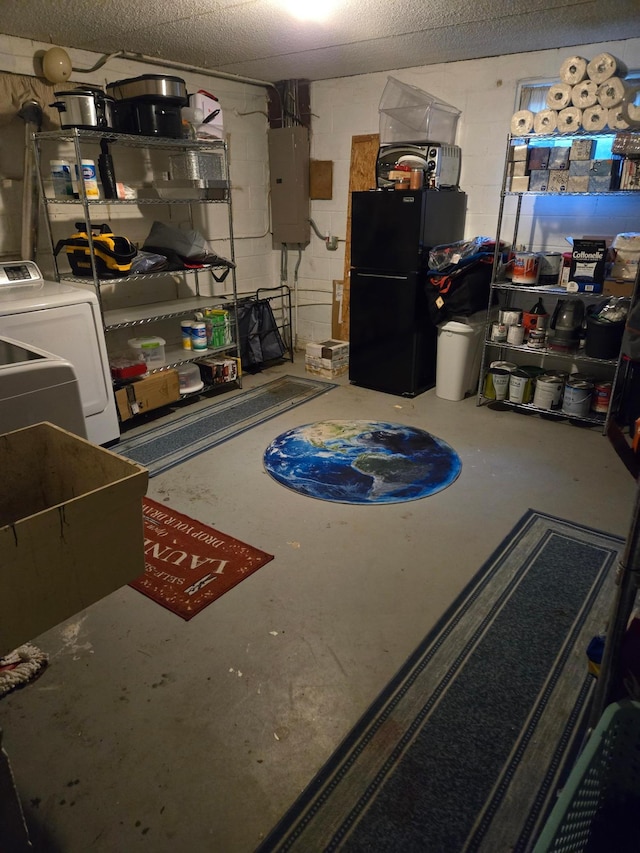 basement featuring washer / dryer, electric panel, and black fridge