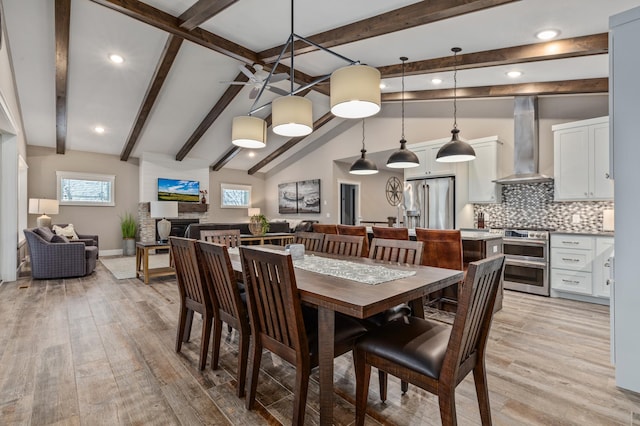 dining area with light wood-type flooring and lofted ceiling with beams