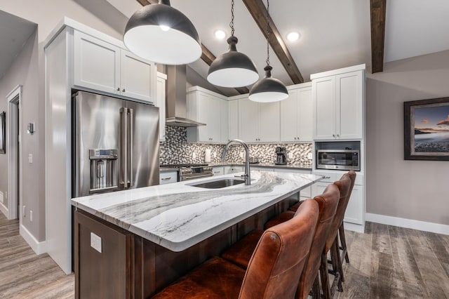 kitchen featuring beam ceiling, high end appliances, wood-type flooring, decorative backsplash, and wall chimney exhaust hood