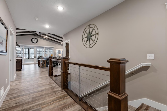 corridor with hardwood / wood-style floors and lofted ceiling with beams