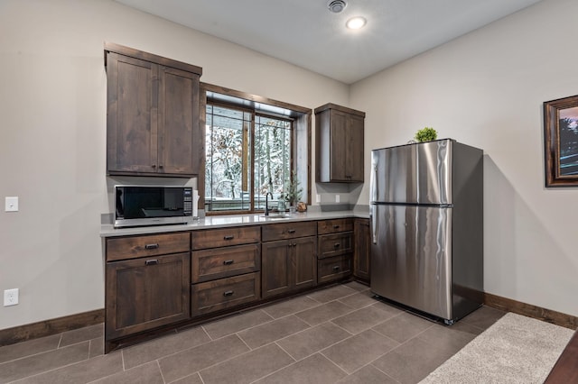 kitchen with tile patterned floors, appliances with stainless steel finishes, sink, and dark brown cabinets