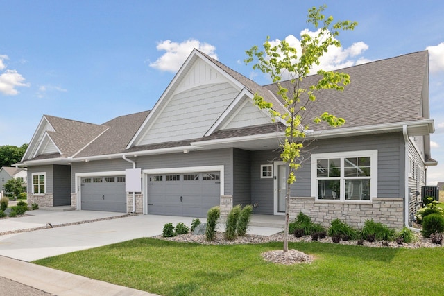 craftsman-style home with driveway, stone siding, an attached garage, and a front lawn