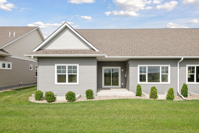 back of house featuring a shingled roof, a lawn, and a patio area