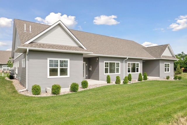 view of front facade with a patio area, a shingled roof, and a front yard