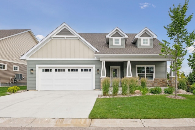 craftsman-style home with board and batten siding, concrete driveway, a front lawn, and an attached garage