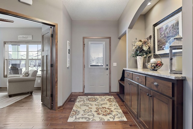 doorway with dark wood-type flooring and a textured ceiling