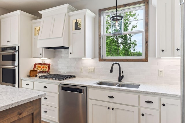 kitchen with white cabinetry, appliances with stainless steel finishes, sink, and decorative light fixtures