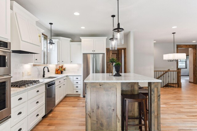 kitchen with decorative light fixtures, a kitchen island, sink, and stainless steel appliances