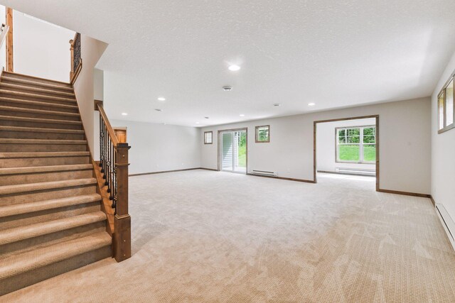 unfurnished living room featuring a textured ceiling, baseboard heating, and light carpet