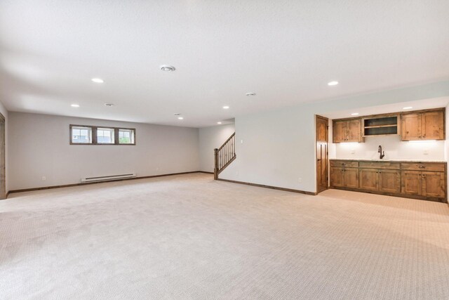 unfurnished living room with light carpet, baseboard heating, and sink