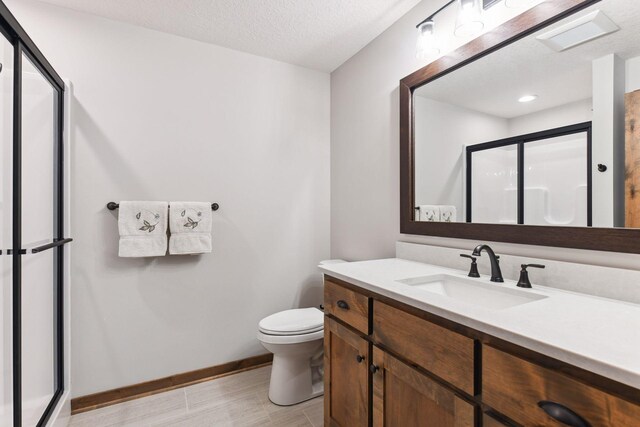 bathroom featuring a shower with door, vanity, a textured ceiling, and toilet