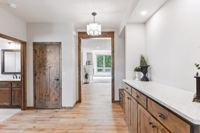 hallway featuring a chandelier, sink, and light hardwood / wood-style floors