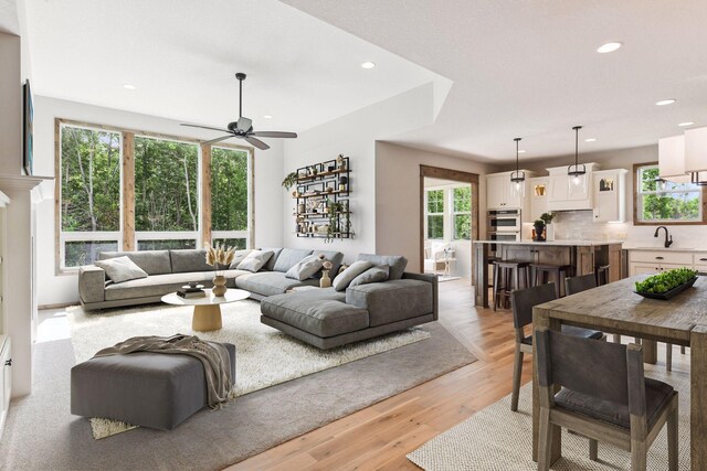 living room featuring ceiling fan, sink, a wealth of natural light, and light hardwood / wood-style flooring