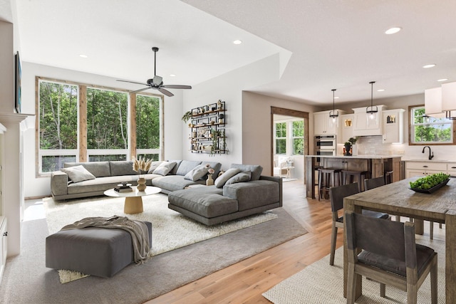 living room with light wood-type flooring, sink, and ceiling fan