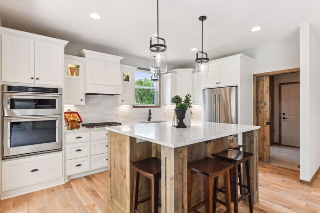 kitchen featuring a kitchen breakfast bar, stainless steel appliances, a kitchen island, and white cabinetry