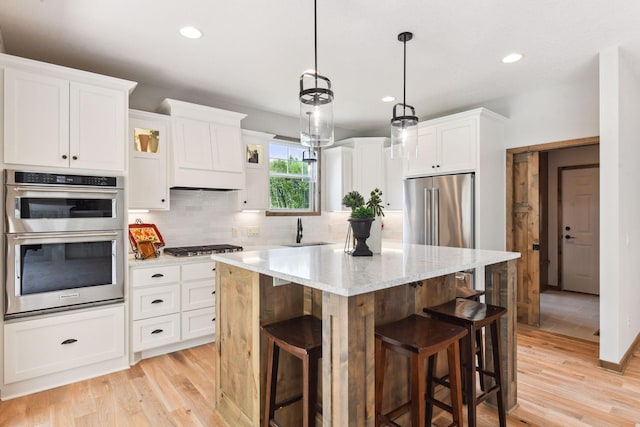 kitchen featuring appliances with stainless steel finishes, a kitchen island, white cabinetry, and a kitchen bar