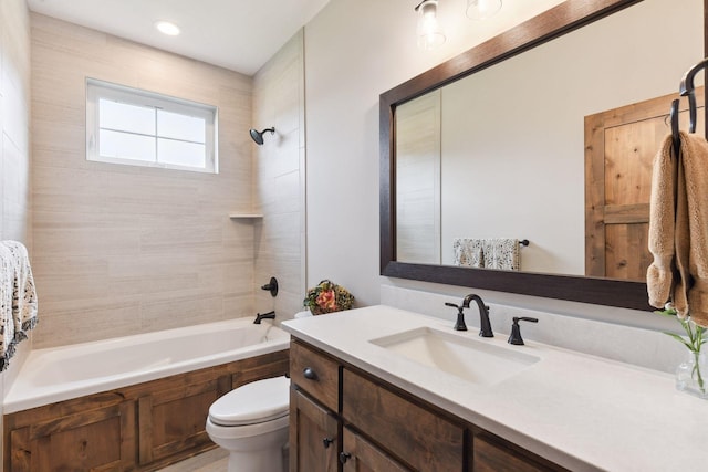 full bathroom featuring vanity, tiled shower / bath, and toilet