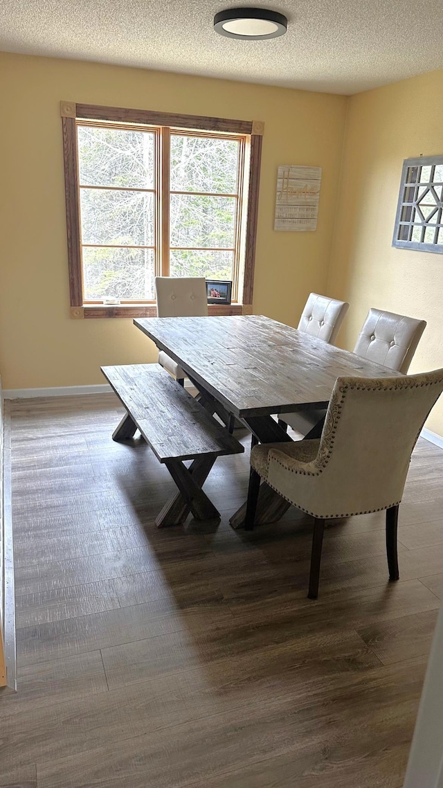 dining room with baseboards, a textured ceiling, and wood finished floors