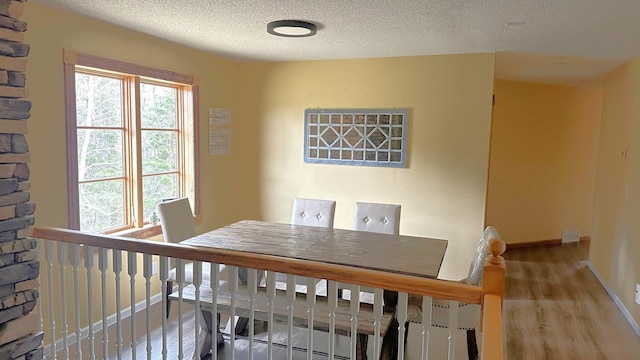 dining space with a textured ceiling, baseboards, and wood finished floors
