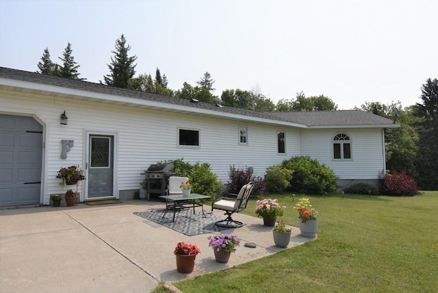 rear view of property featuring a lawn, an attached garage, and a patio area