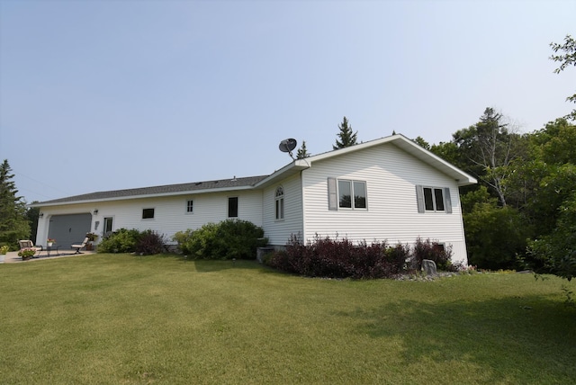 rear view of house featuring a lawn and a garage