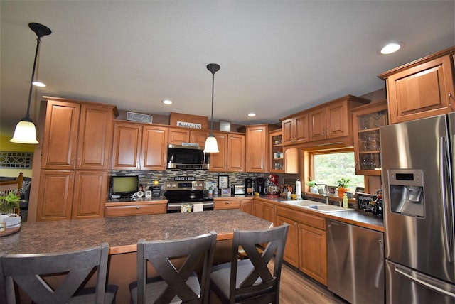 kitchen with brown cabinets, a sink, stainless steel appliances, backsplash, and glass insert cabinets