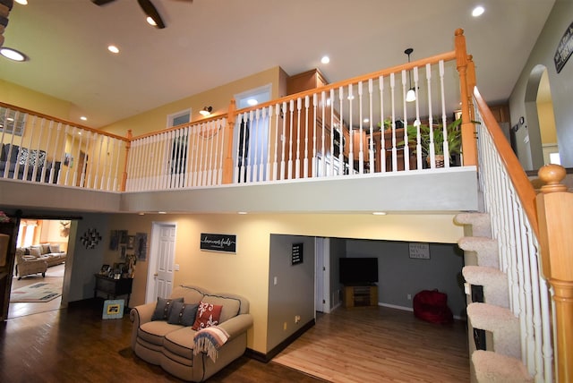 living area with wood finished floors, baseboards, a high ceiling, stairway, and recessed lighting