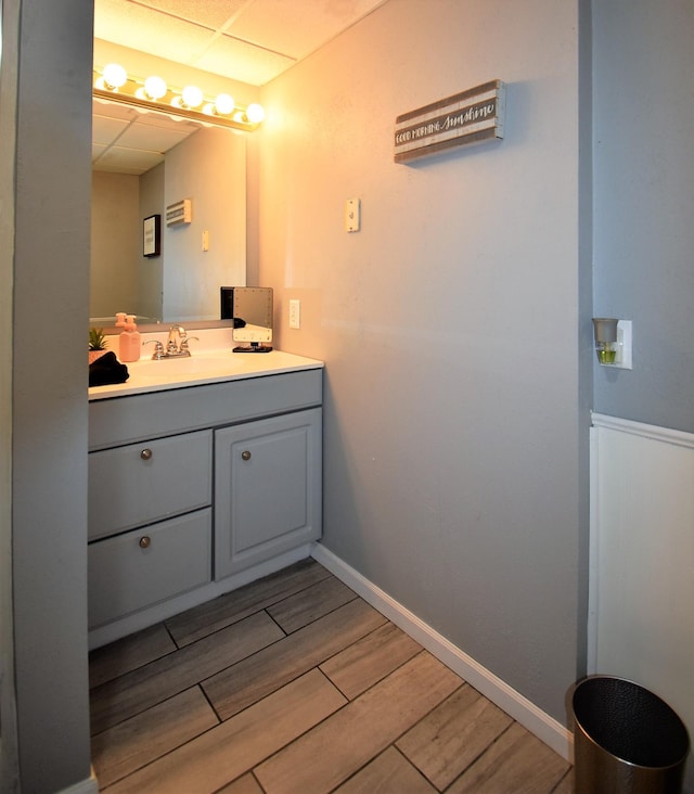 bathroom with wood tiled floor, baseboards, vanity, and a paneled ceiling