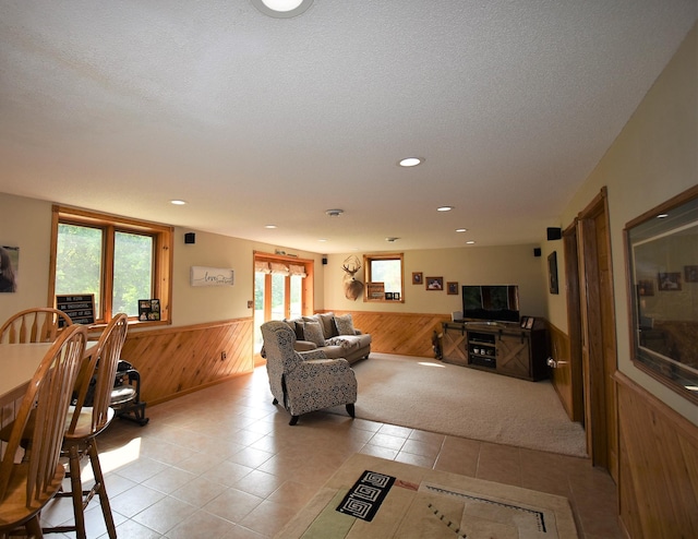 living area featuring wooden walls, a wainscoted wall, light tile patterned floors, and a textured ceiling