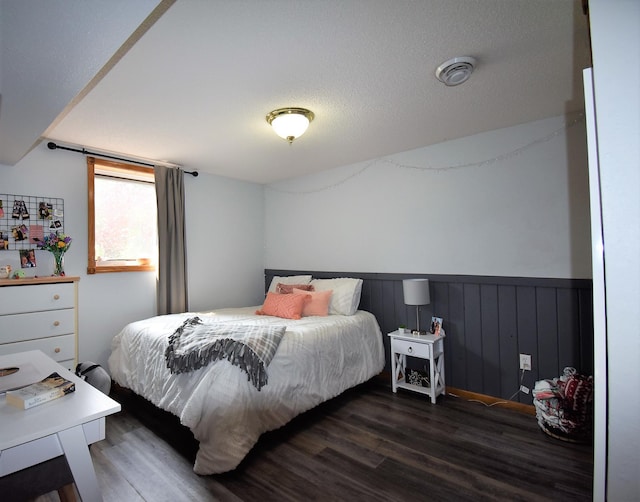 bedroom with a wainscoted wall and wood finished floors