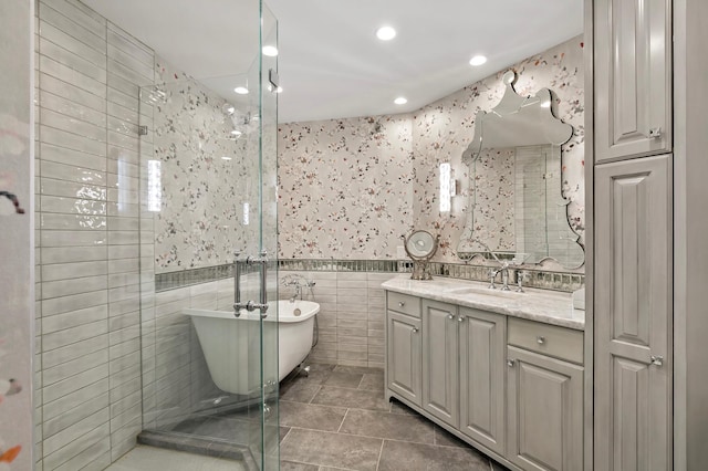 bathroom featuring tile patterned flooring, tile walls, plus walk in shower, and vanity