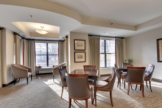 dining area featuring light colored carpet and a raised ceiling