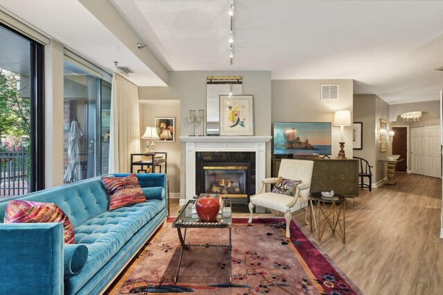 living room with hardwood / wood-style floors, rail lighting, and a tiled fireplace