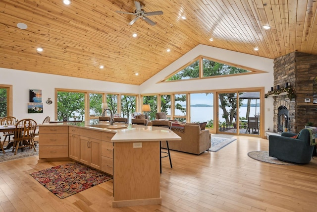 kitchen featuring light brown cabinetry, a center island with sink, high vaulted ceiling, and light hardwood / wood-style flooring