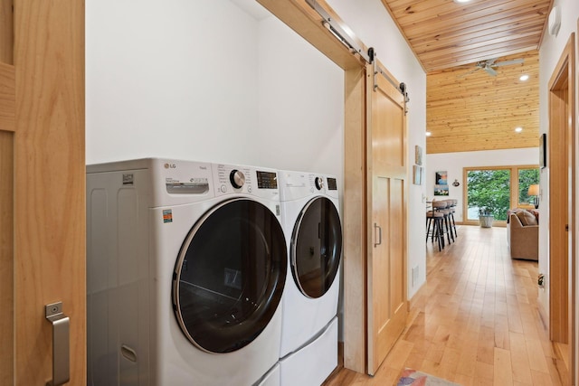 laundry room featuring a barn door, wood ceiling, independent washer and dryer, and light hardwood / wood-style flooring