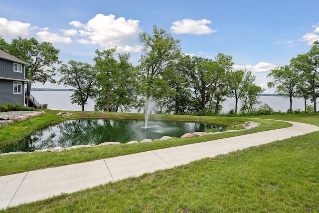 view of property's community with a water view and a yard