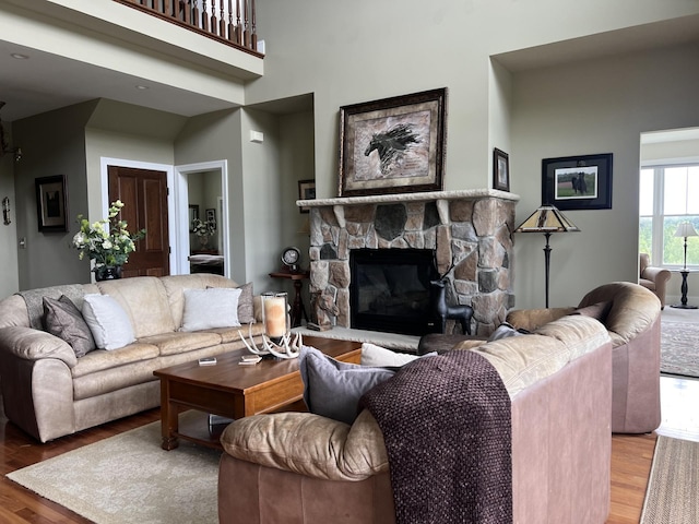 living room featuring a towering ceiling, a fireplace, and hardwood / wood-style floors