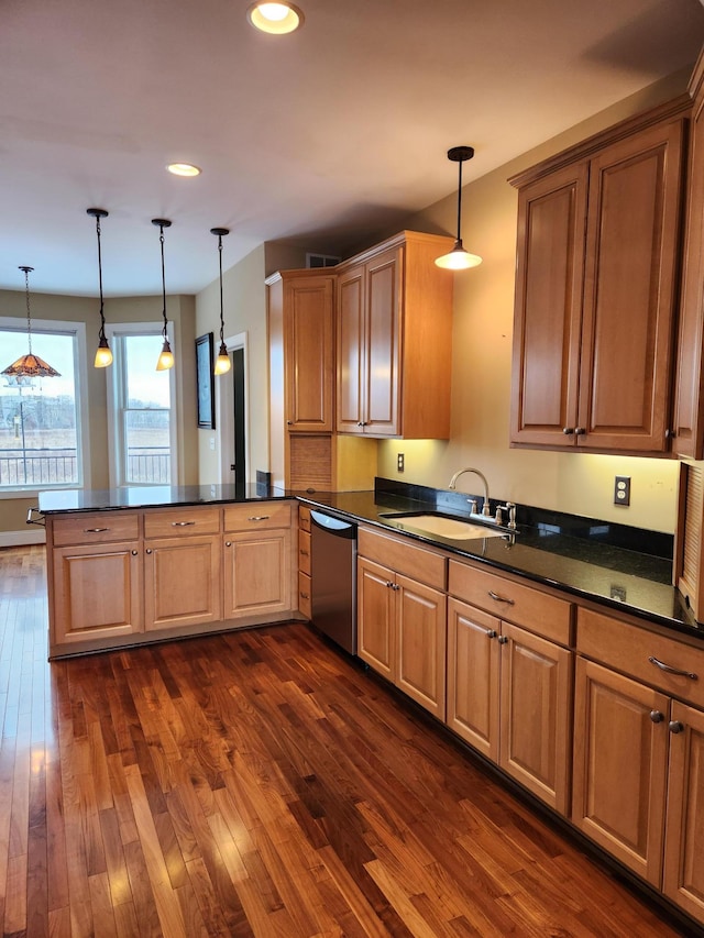 kitchen featuring dishwasher, a peninsula, dark countertops, and a sink