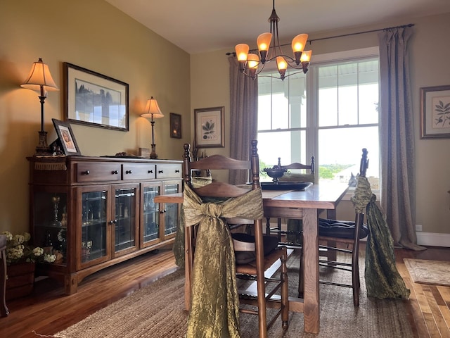 dining room with baseboards, an inviting chandelier, and wood finished floors