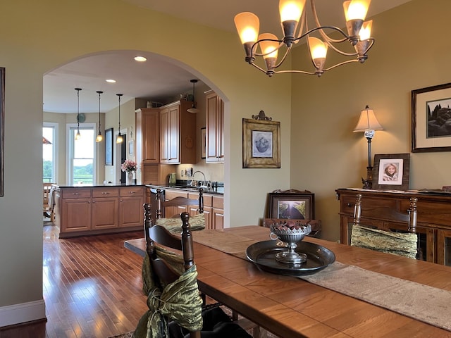 dining room featuring dark wood-style floors, arched walkways, and an inviting chandelier