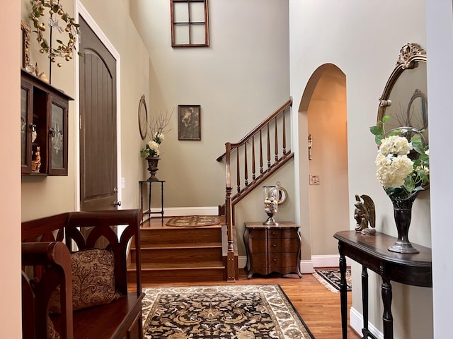 entryway featuring stairway, light wood-type flooring, arched walkways, and baseboards